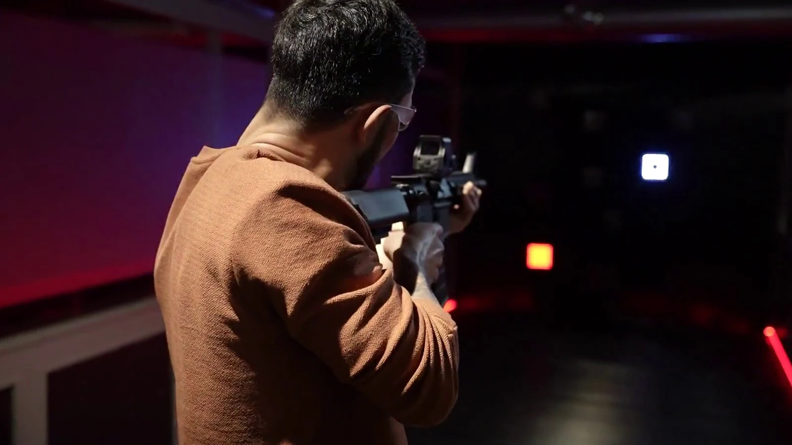 A guest practising with a rifle in Aldgate’s red-lit lanes
